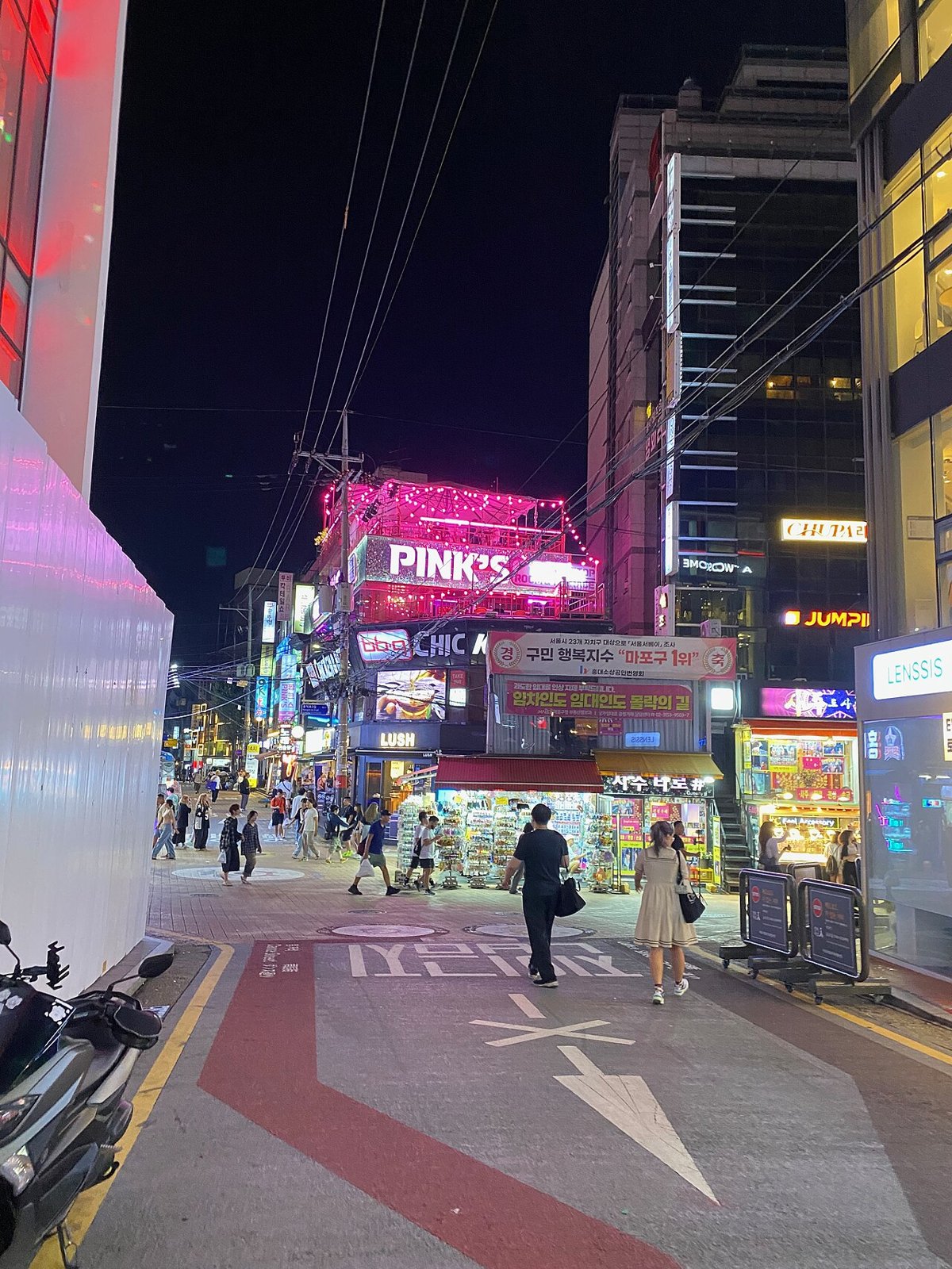 21. 2024년 8월 19일, 홍대 앞 밤거리. 음식점과 상점 사이를 걷는 사람들의 모습으로, 특정 대학생 모임을 촬영한 사진은 아니다.